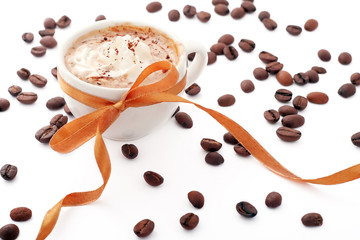 cup of coffee with cream, coffee beans and golden ribbon