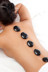pretty woman receiving a therapy with hot stones