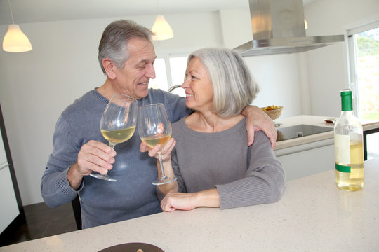 Senior Couple Drinking Wine In Home Kitchen