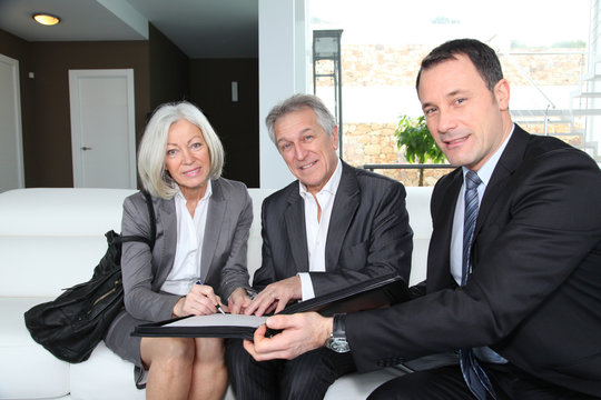 Senior couple signing financial contract for property purchase