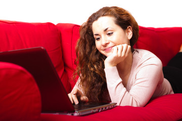 junge Frau mit Laptop auf Sofa liegend