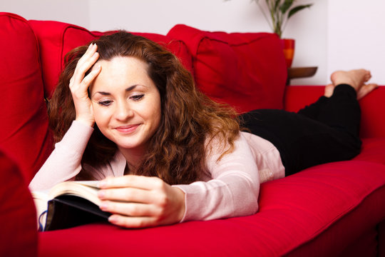 junge Frau mit Buch auf Sofa