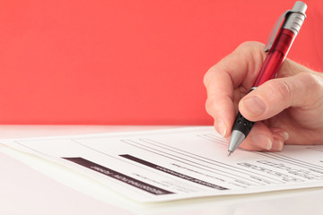 Red Themed Pen in Hand Completing Form