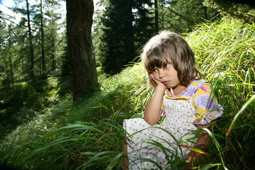 bambina seduta nel bosco