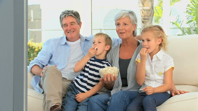 Family watching tv while eating popcorn