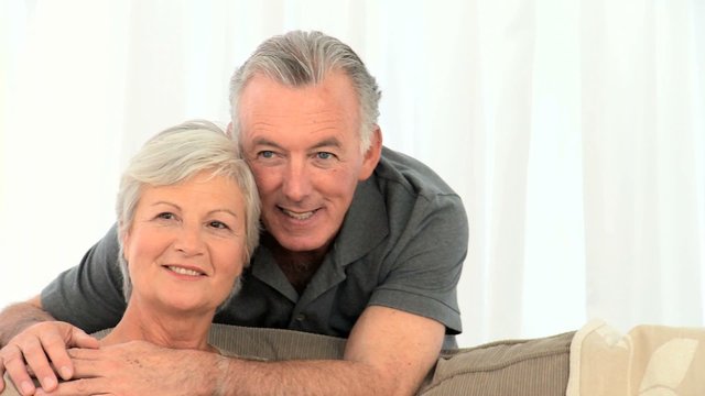 Retired couple looking at the camera in the living room