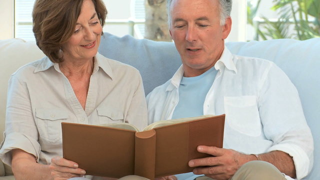 Senior couple looking at a photos album in the living room
