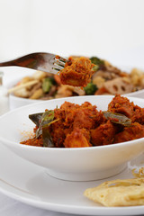 A fork picks a piece of rendang chicken