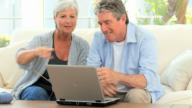Retired couple talking in front of a computer in the living room