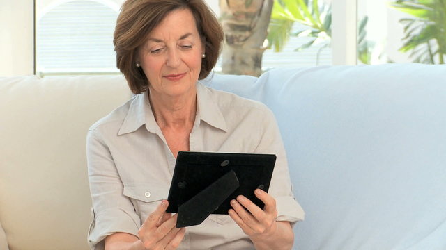 Retired woman looking at a photo on the sofa