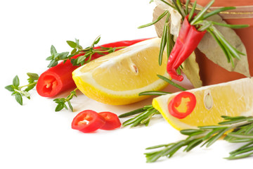 Chili pepper, lemon, thyme and rosemary on white.
