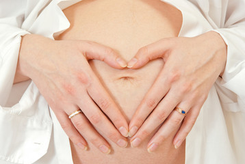 Woman holding hands on belly in shape of heart