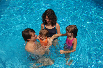 Happy family with two kids having fun in swimming pool