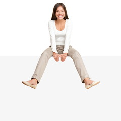 Woman sitting on billboard sign edge