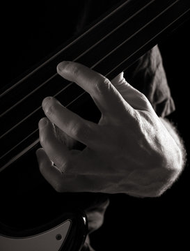 playing fretless electric bass guitar; toned monochrome image;