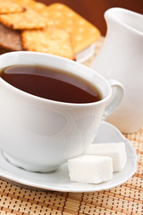 A cup of black tea with a lump sugar and crackers for breakfast