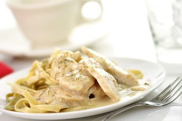 chicken with spinach pasta in a white plate