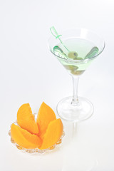 Peach dessert and green alcohol cocktail with martini and olives