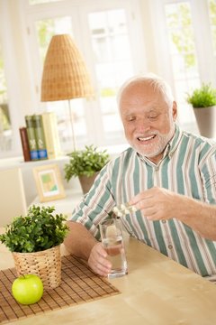 Smiling old man taking medication