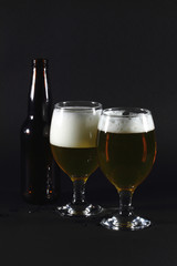 Two glasses full with beer and  beer bottle.