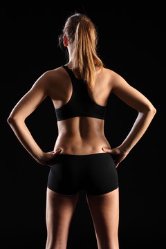 Back of fit young woman in black sports outfit
