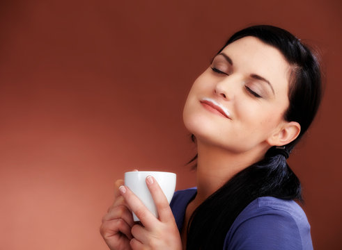Young woman with coffe and a rest of milk on her mouth