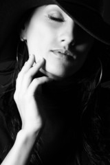 Attractive brunette girl in the hat gently touch your face. BW