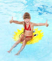 Child sitting on inflatable ring thumb up.