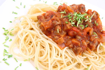Spaghetti bolognese on a plate decorated with some chives