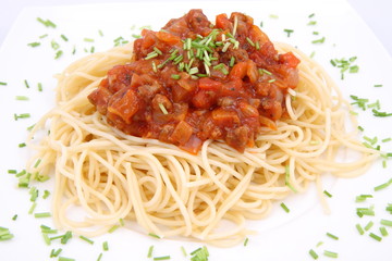 Spaghetti bolognese on a plate decorated with some chives
