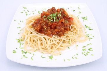 Spaghetti bolognese on a plate decorated with some chives