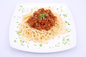 Spaghetti bolognese on a plate decorated with some chives