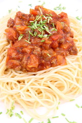 Spaghetti bolognese on a plate decorated with some chives
