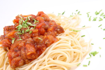 Spaghetti bolognese on a plate decorated with some chives