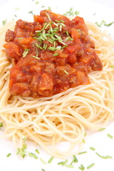 Spaghetti bolognese on a plate decorated with some chives