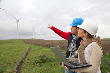 Engineers working by wind turbines field