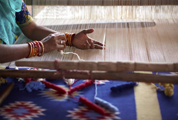 Woman hand weaving a carpet with a manual loom in India - 29748860