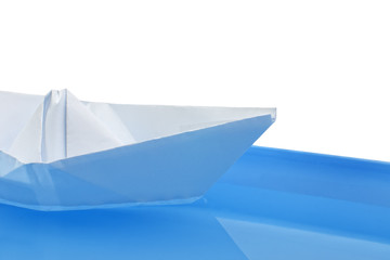 folded paper ship on blue water with selective focus on white