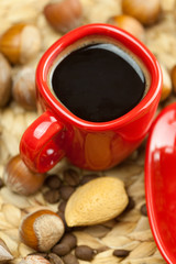 cake on a plate, nuts and a cup of coffee on a wicker mat