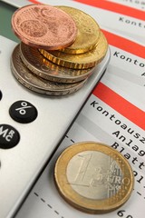 Taschenrechner mit Kontoauszügen und Münzen