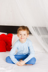 boy  sits on a bed in a comfortable situation © OlgaKhorkova
