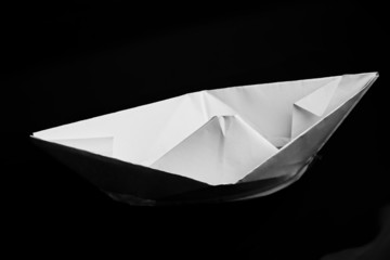 Closeup of folded paper ship on black with selective focus