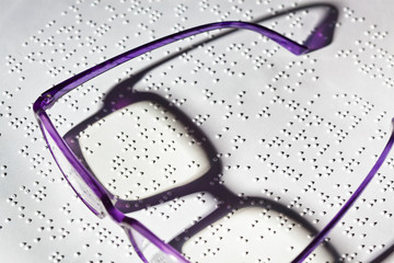 Brille und Buch in Blindenschrift. Braille