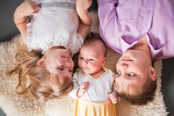 Three children lie on a fur skin..