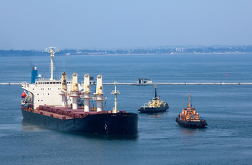 Cargo ship leaves port with tugs assistance