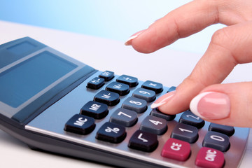 Fingers and calculator on blue background