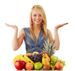 Young woman at the table with variety of fruits on white