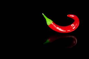 Red hot chili pepper on black background with reflection