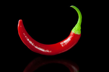 Red hot chili pepper on black background with reflection