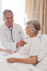 Obraz premium Senior doctor taking the heartbeat of his patient